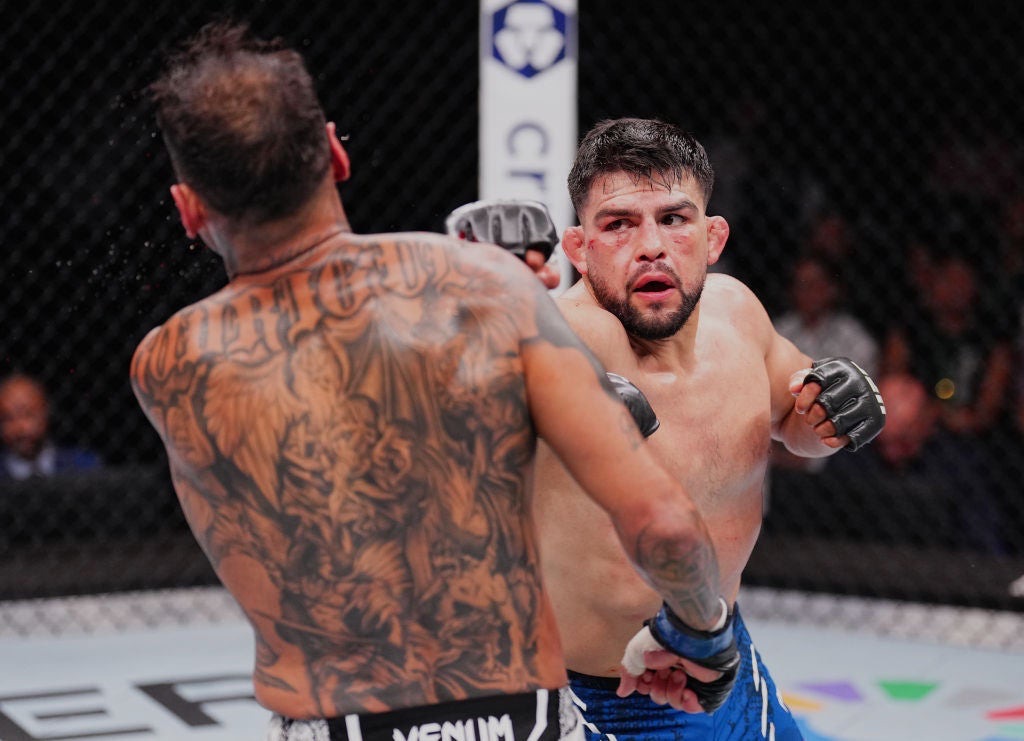 Kelvin Gastelum bloodied and pressing forward in blue trunks